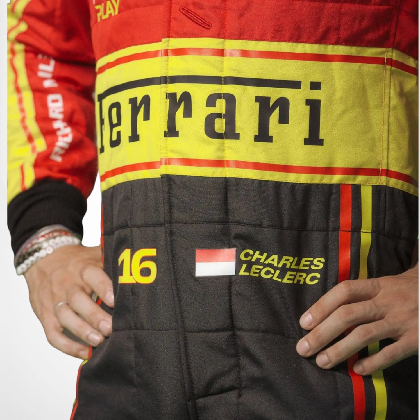 Close-up of the Monza 2023 suit fabric worn by Charles Leclerc, showing fine stitching, red sponsor logos, and the vibrant yellow-red color combination.