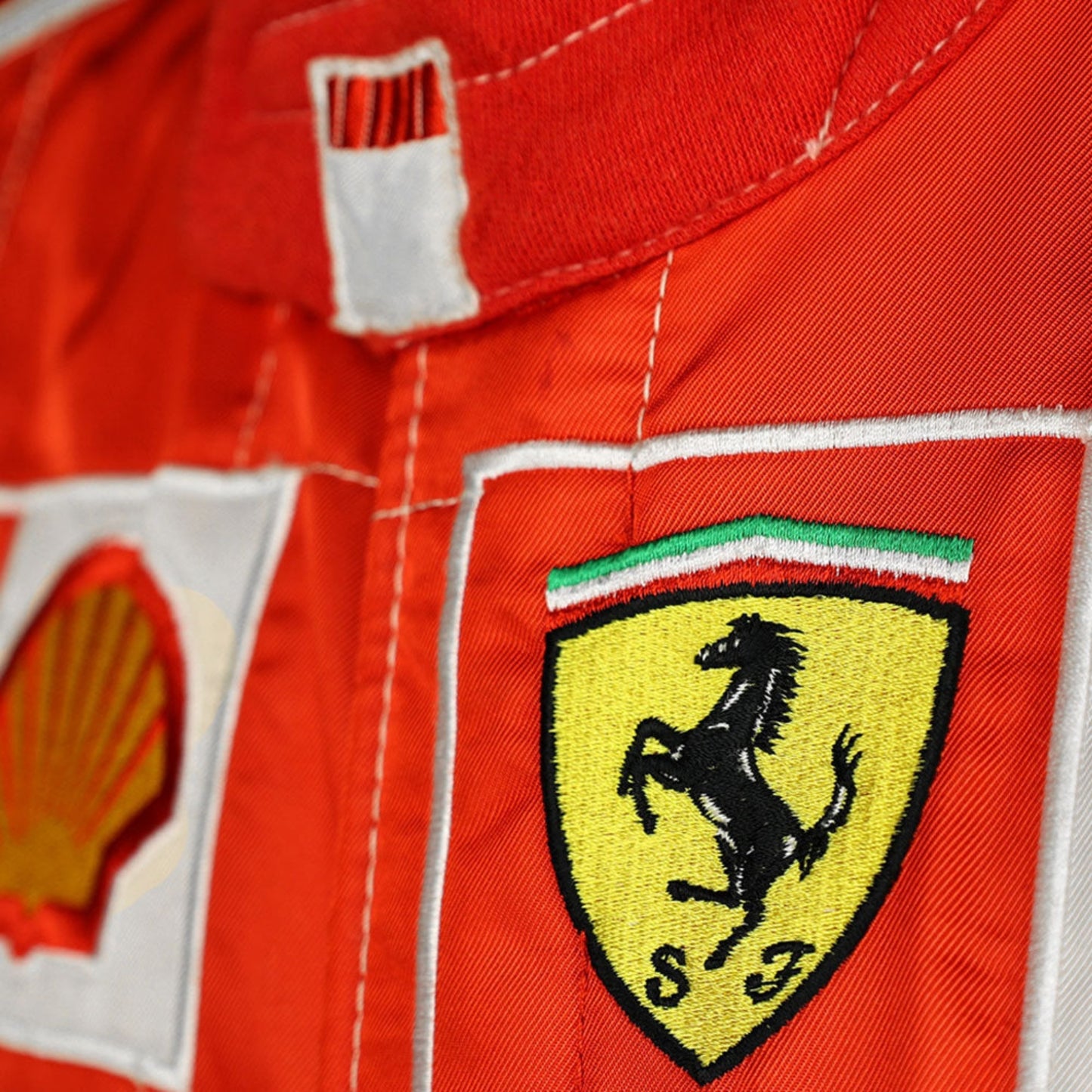 Close-up shot of Schumacher’s 2006 race suit, highlighting the detailed stitching, premium red material, and signature white branding elements.