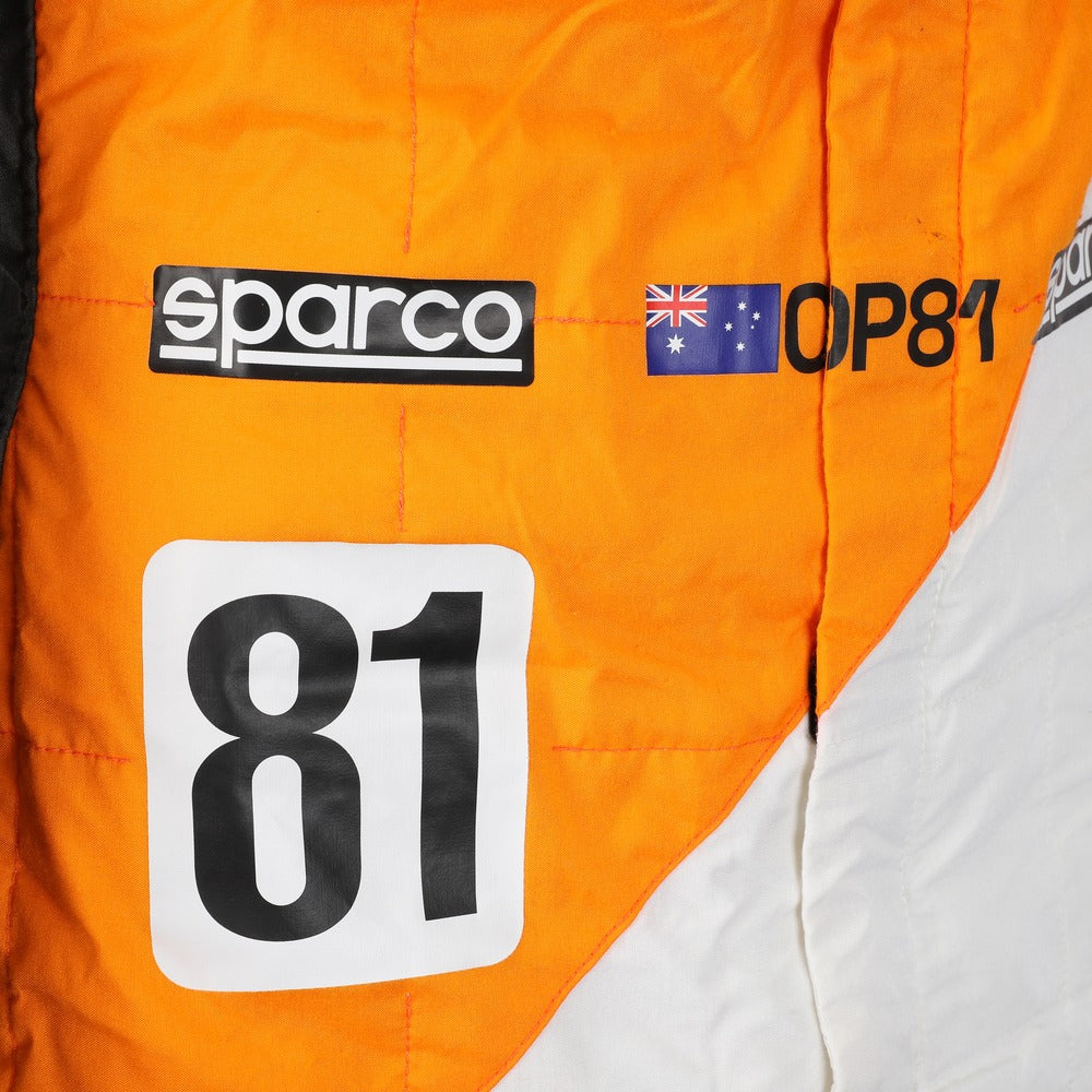 Close-up of Oscar Piastri’s 2023 Spanish GP race suit, emphasizing high-resolution logos, stitch detailing, and special edition ‘Triple Crown’ patchwork.