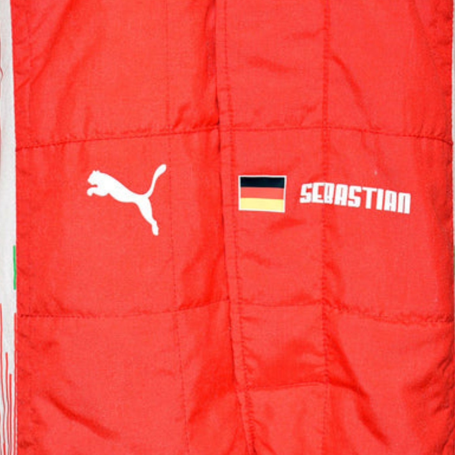 Close-up of Sebastian Vettel’s 2018 racing suit, emphasizing the fine stitching, vivid red texture, and white contrast elements.