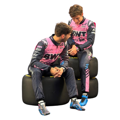 Pierre Gasly and Franco Colapinto in racing suits sitting on racing tires against a white background