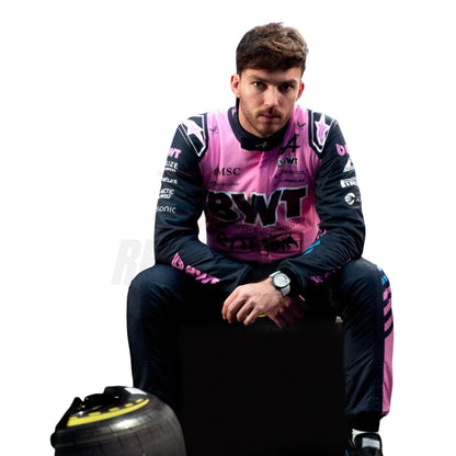 Pierre Gasly wearing a pink and black racing suit with visible branding, sitting on a racing tire.