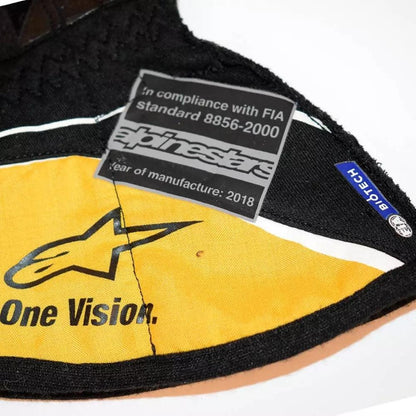 Close-up of a Nico Hulkenberg 2018 F1 racing gloves with a brand label and compliance text on a white background