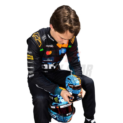 Sitting View of Oscar Piastri wearing a McLaren Monaco GP F1 racing suit holding a helmet with sponsor logos - Revex Gear