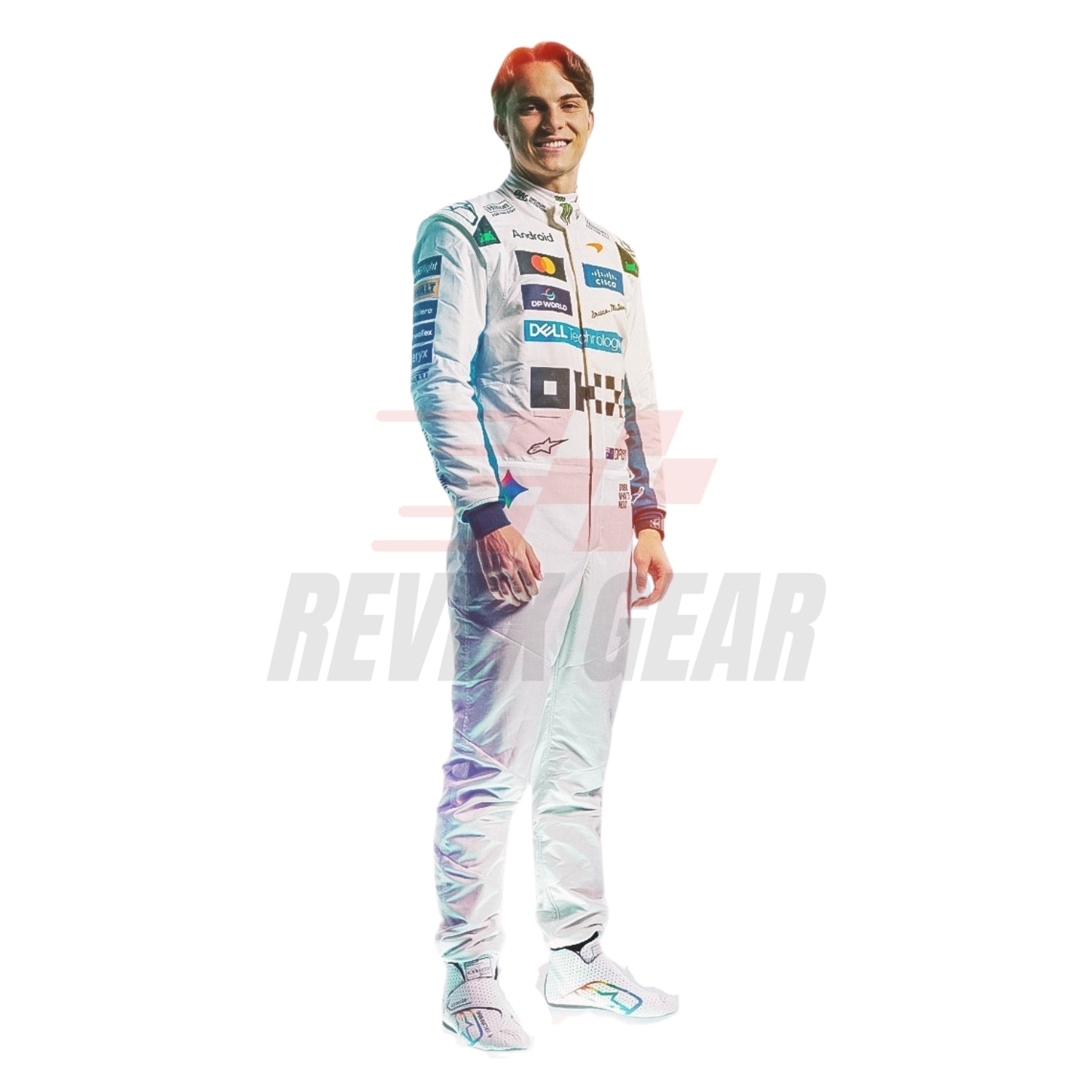 A full-body cutout of a smiling Oscar Piastri in a McLaren 2026 British GP white F1 racing suit with colorful sponsor logos, standing against a plain white background. A faint 'REVEX GEAR' watermark is visible across the center.